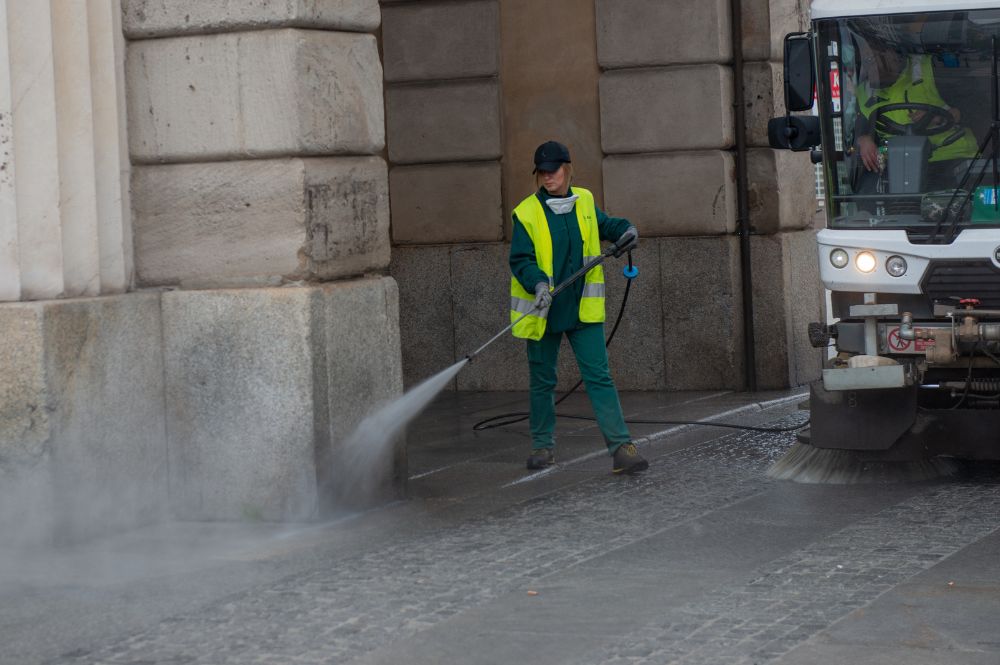 Operario limpiando calle aspersión agua